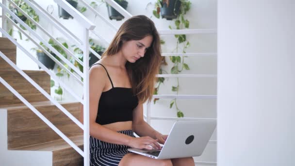 Carismática hermosa dama trabajando concentrada en su cuaderno, ella sentada en las escaleras en el edificio de negocios 4k — Vídeos de Stock