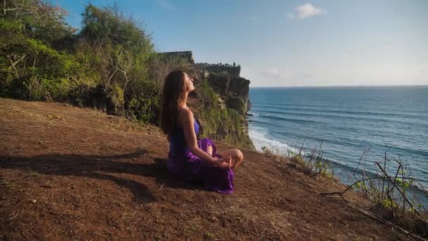 Bela e saudável respiração feminina suavemente e senta-se em pose de lótus ou sukhasna meditando ou praticando ioga e pranayama — Vídeo de Stock