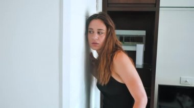 Paranoid woman is shocked looking into the peephole. The female wants to hide from an unexpected guest and shows shh. 4k