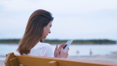 Güzel gülümseyen kız gölün arka planında Spartfone 'u tek başına kullanır.