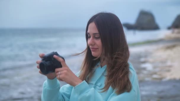 Retrato mujer hipster es un fotógrafo profesional con cámara. Hace fotos sobre el fondo del océano en el crepúsculo. 4k — Vídeos de Stock