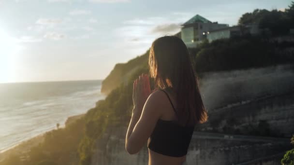 O fată frumoasă se roagă să privească cerul cu speranţă, aproape. Silueta de femeie tânără visând în sus apus de soare în aer liber ocean fundal 4k . — Videoclip de stoc