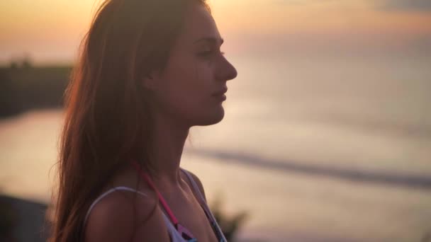 Schöne Mädchen betet und blickt hoffnungsvoll in den orangen Himmel, aus nächster Nähe. Silhouette einer jungen Frau träumt Blick nach oben Sonnenuntergang im Freien Ozean Hintergrund 4k. — Stockvideo
