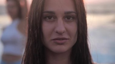 Renkli arka planda gülümseyen güzel bir kızın yakın plan portresi yalnız başına kameraya bakıyor, güzel uzun saçları ve tatlı bir gülümsemesi var. İnsanlar ve duygular. 4k