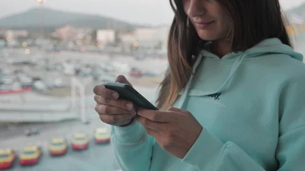 Side view brunette woman using smartphone near airport window. Girl is texting message with view of plane background. 4k