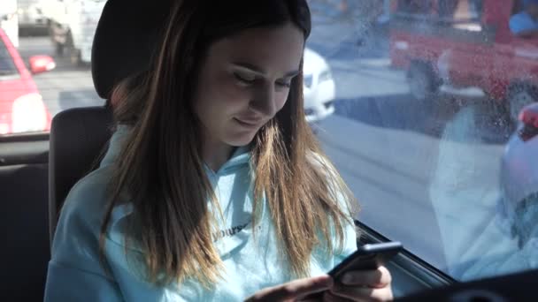 Mujer joven viajando en autobús y haciendo clic en smartphone su teléfono inteligente. Chica está viajando en el coche delante de la ventana 4k — Vídeos de Stock
