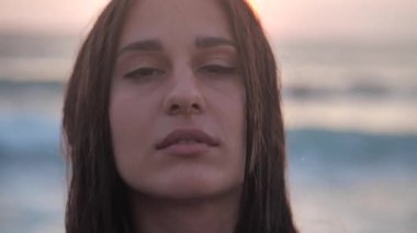 Renkli arka planda gülümseyen güzel bir kızın yakın plan portresi yalnız başına kameraya bakıyor, güzel uzun saçları ve tatlı bir gülümsemesi var. İnsanlar ve duygular. 4k