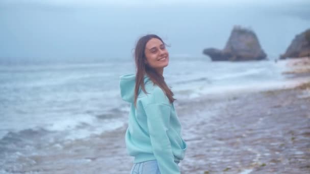 Porträtt hipster kvinna i en turkos tröja på havet bakgrund i skymningen. 4k — Stockvideo