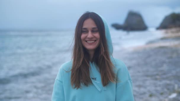 Portrait hipster woman in a turquoise sweatshirt at ocean background in twilight. 4k — Stock Video