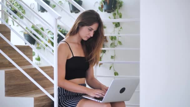 Carismática hermosa dama trabajando concentrada en su cuaderno, ella sentada en las escaleras en el edificio de negocios 4k — Vídeos de Stock