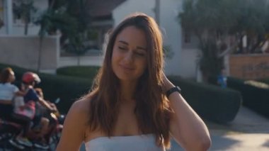 Kameraya bakarken çıplak omuzlarıyla poz veren çekici genç bir kız. Hüküm giydi, hareket etti ve saçını düzeltti.