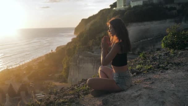 ヨガ瞑想を行う平和的な女の子は、日没の海岸遅い動きを味わう。バリ島、メラスティビーチ4k — ストック動画