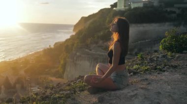 Güzel genç kız yoga meditasyonu yapıyor. Gün batımı konsepti ağır çekim. Yogiler gün batımında dua eder. Doğa ile birlik 4k