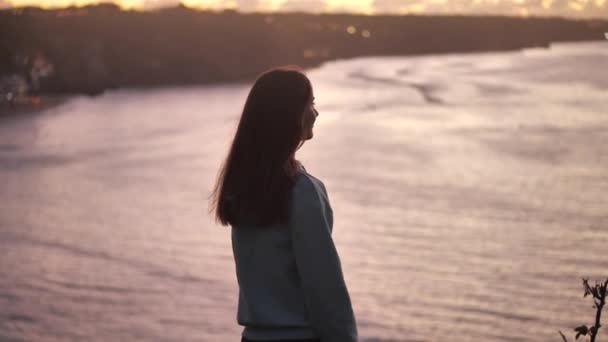 Närbild porträtt av vacker ung kvinna tittar upp lyfta armarna upp med blåst hår njuter av fridfullt hav vid solnedgången 4k — Stockvideo