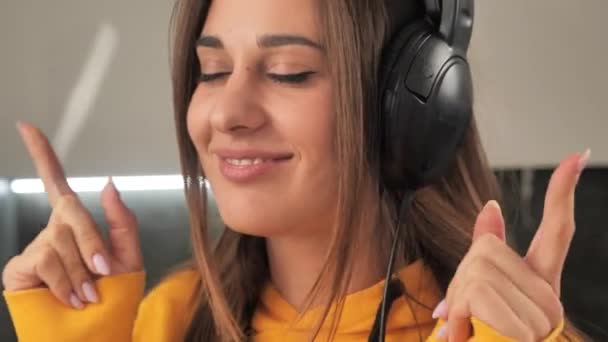 Γκρο πλαν πορτρέτο ενός κοριτσιού που ακούει μουσική με ακουστικά. Κορίτσι κοιτάζοντας απευθείας στην κάμερα 4k — Αρχείο Βίντεο