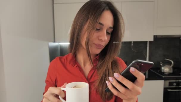 The girl is drinking coffee and receives a notification on the phone about the successfully completed operation. 4k — Stock Video