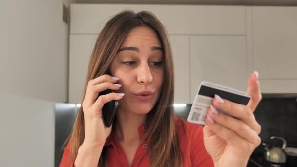 Egy boldog és mosolygós nő, aki kártyával fizet a mobilján, hogy kifizesse a számlákat. 4k — Stock videók