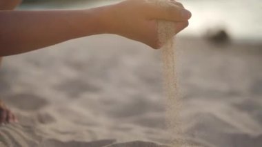 Kumsalda elinde kum tutan bir kadın. 4k