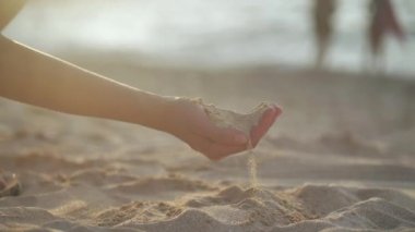 Kumsalda elinde kum tutan bir kadın. 4k