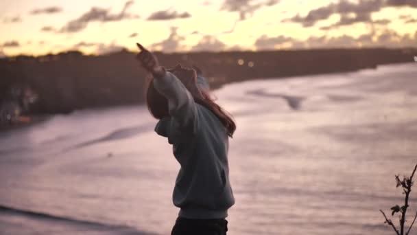 Közeli portré gyönyörű fiatal nő felnéz emelje fel a karját a szél fúj haj élvezi békés tengerparton naplementekor 4k — Stock videók