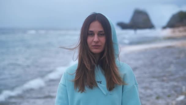 Portrait hipster woman in a turquoise sweatshirt at ocean background in twilight. 4k — Stock Video