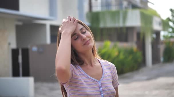 Attraente giovane donna che cammina per le strade soleggiate della città e chatta con gli amici, utilizzando il cellulare all'aperto, sfondo urbano 4k — Video Stock