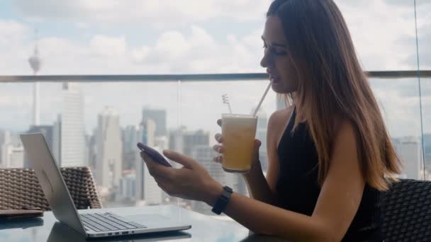 Ένας επιχειρηματίας κάθεται σε ένα εστιατόριο σε ένα φορητό υπολογιστή, κάνει κλικ στο τηλέφωνο και πίνει χυμό 4k — Αρχείο Βίντεο