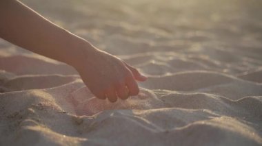 Kumsalda elinde kum tutan bir kadın. 4k