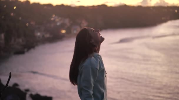 Primer plano retrato de una hermosa joven mirando hacia arriba explorando mindfulness contemplando la espiritualidad con el viento soplando pelo disfrutando de la tranquila playa al atardecer 4k — Vídeo de stock