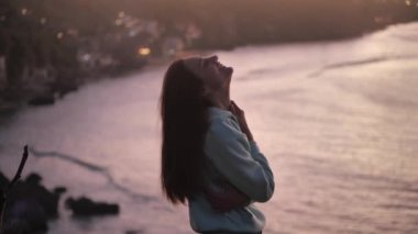 close up portrait of beautiful young woman looking up exploring mindfulness contemplating spirituality with wind blowing hair enjoying peaceful seaside at sunset 4k