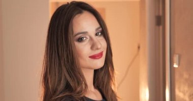Kırmızı ruj makyajlı muhteşem esmer kadının portresi arka planda izole edilmiş kameraya gülümsüyor.
