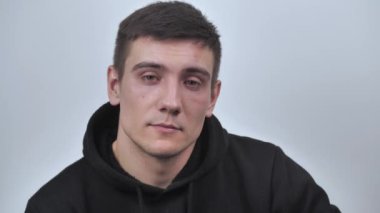 Çekici adam kameraya bakarak samimi bir şekilde gülümsüyor, beyaz bulanık arka planda izole edilmiş. Kapatın. 4k