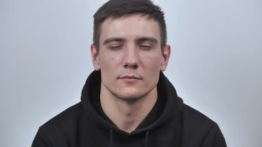 Gözlerini kısarak bakan bir gencin portresi.