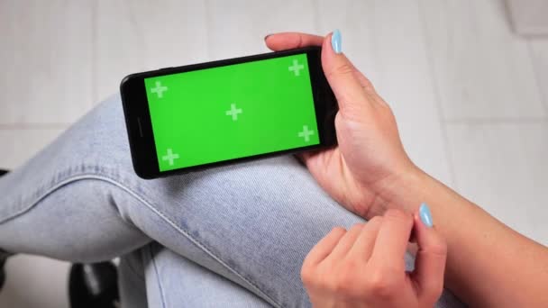 Απασχολημένη νεαρή γυναίκα κρατώντας mockup smartphone αγγίζοντας και σαρώνοντας σε πράσινη οθόνη surfing κοινωνικά δίκτυα σε εξωτερικούς χώρους studia 4k — Αρχείο Βίντεο