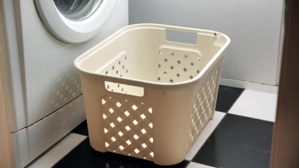 Throwing dirty laundry inside laundry basket near washing machine — Stock Video