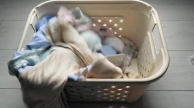 Çamaşır. Kirli çamaşırlar için sepet, büyük bir yıkama için hazırlık, üst manzara. Beyaz çarşaf çamaşır sepetine atılır.