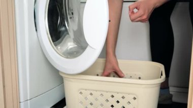 Çamaşır makinesine kirli çamaşır koyan kadın..