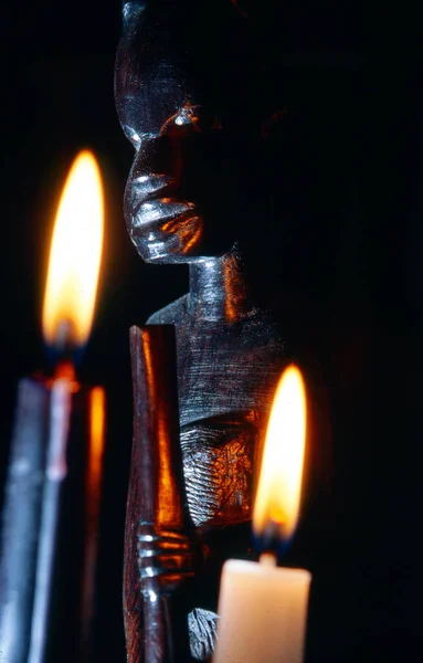 Ciemne Zbliżenie Afrykańskiego Posągu Dwoma Płonącymi Świecami Jedną Czarną Drugą — Zdjęcie stockowe