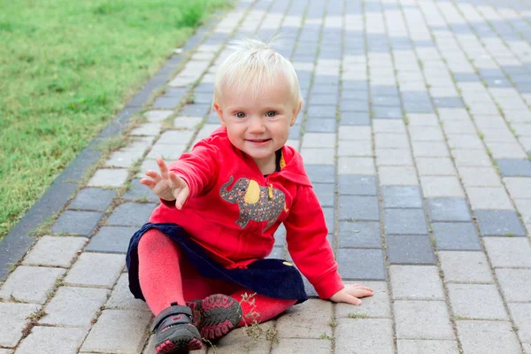 Söt blond baby sitter på marken — Stockfoto