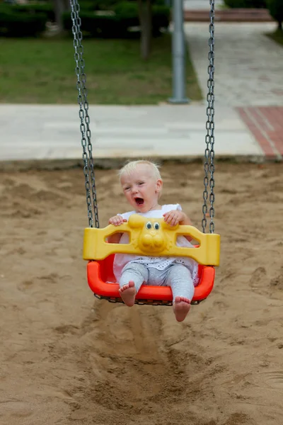 Cute blond baby girl sitting in a swing — Stock Photo, Image
