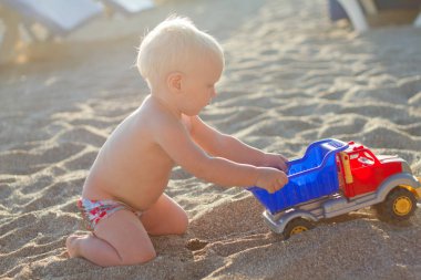 Eğleniyor şirin sarışın bebek oyuncak araba ile sahilde oynarken