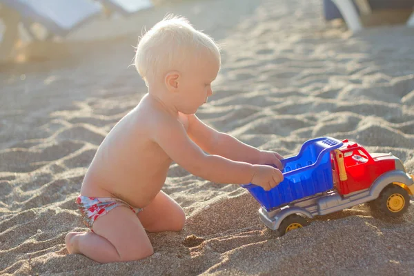 Eğleniyor şirin sarışın bebek oyuncak araba ile sahilde oynarken