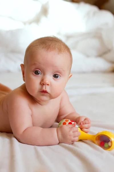 Nyfødt Baby Ligger Naken Sengen Leker Med Leken Ser Mot – stockfoto