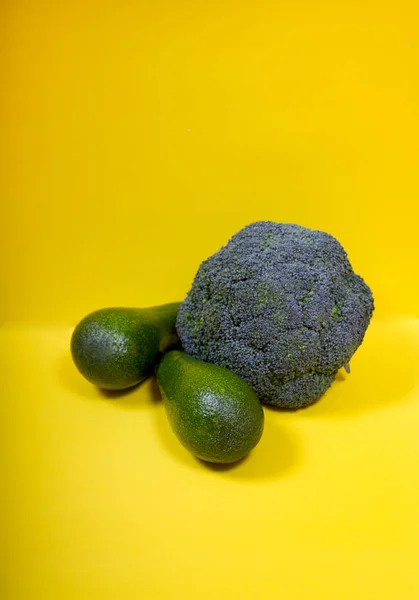 Zwei Grüne Avocados Und Brokkoli Auf Gelbem Hintergrund — Stockfoto