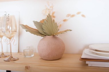 Ahşap bir rafta kurumuş çiçekler ve diğer aletler, modern iç mekan, beyaz duvarlar.