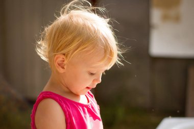 Güneşli bir yaz gününde küvette oyuncaklarla oynayan tatlı sarışın kız.