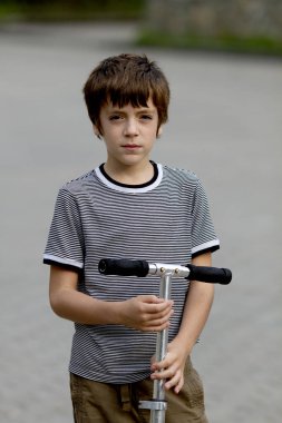 Açık havada bulutlu bir yaz gününde scooter 'ı olan yakışıklı bir genç.