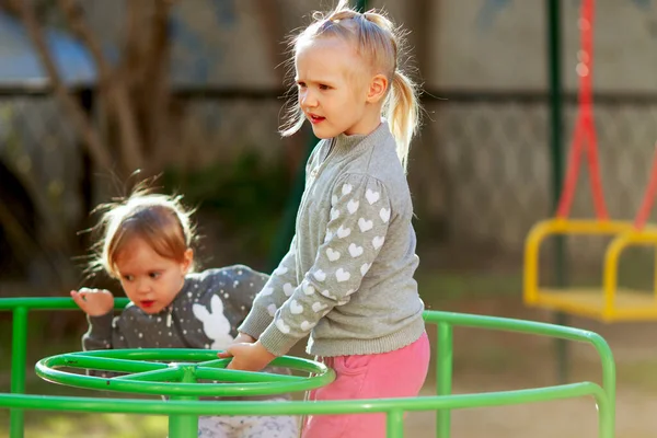 Две Хорошенькие Девочки Сестры Играют Карусели Детской Площадке Солнечный Весенний — стоковое фото