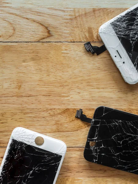 Cracked smartphone screen on wooden background