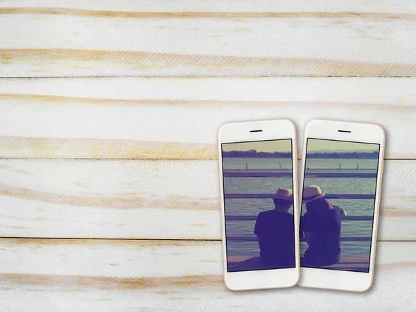 Couples photo on smartphone screen on wood — Stock Photo, Image